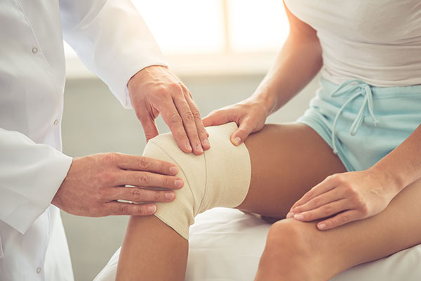 therapist assessing patient's knee