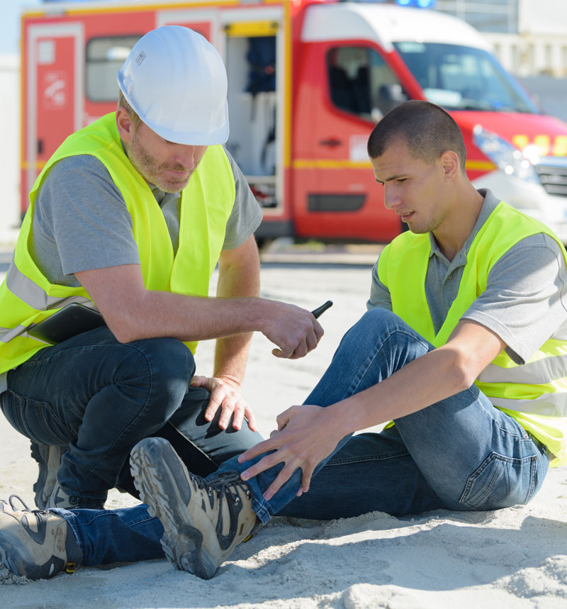 young worker sitting on ground with ankle injury